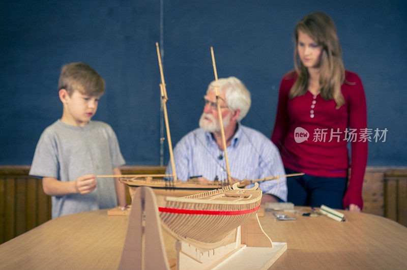 学生们在教室里看一个造船模型