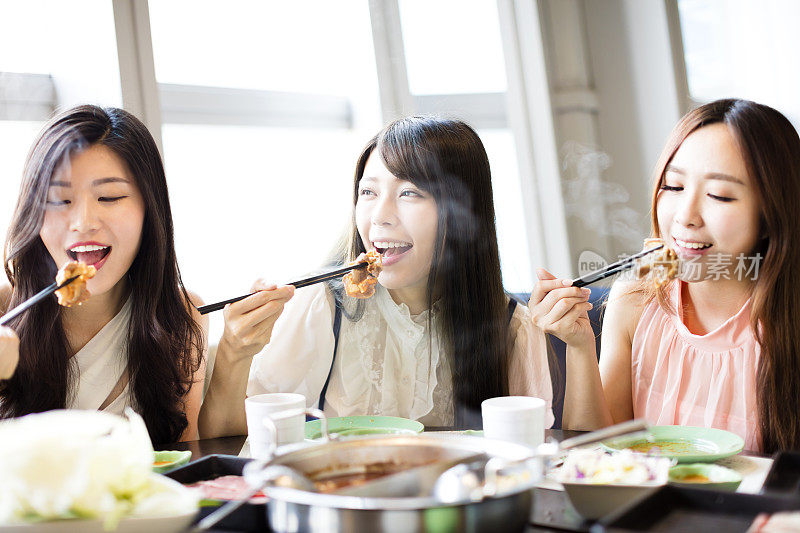 快乐的年轻女性团体吃火锅