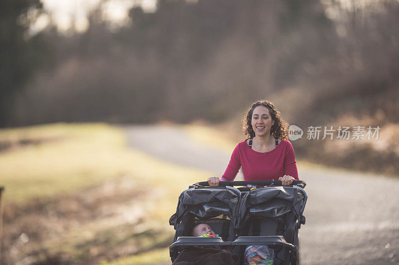 年轻的妈妈推着婴儿车在外面