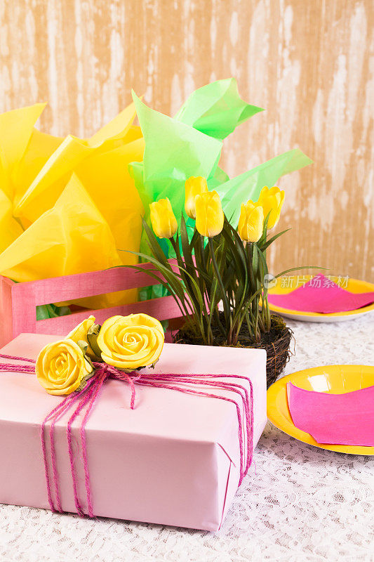 派对时间!黄色的花，礼物，餐桌上的盘子。女性化。
