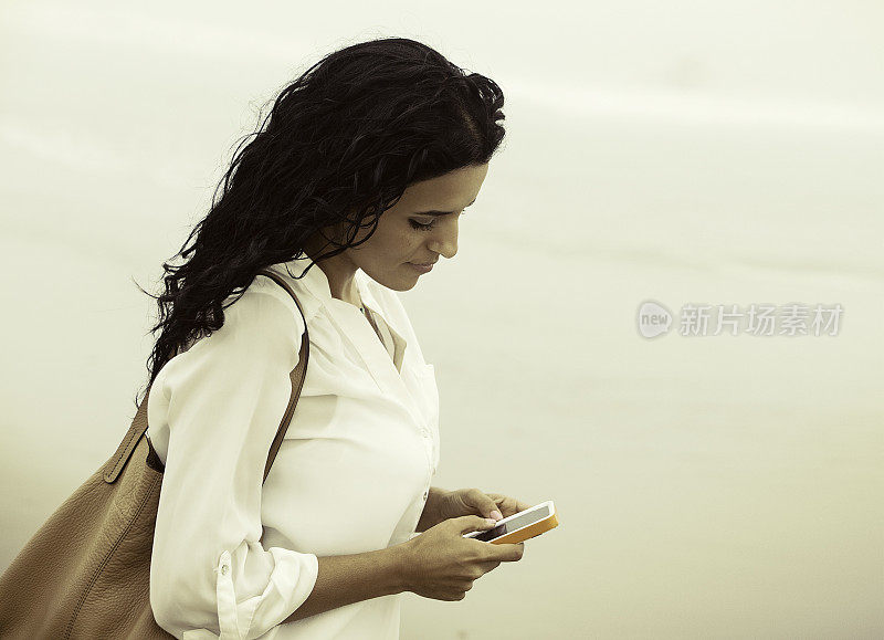 在海滩上看手机的女人