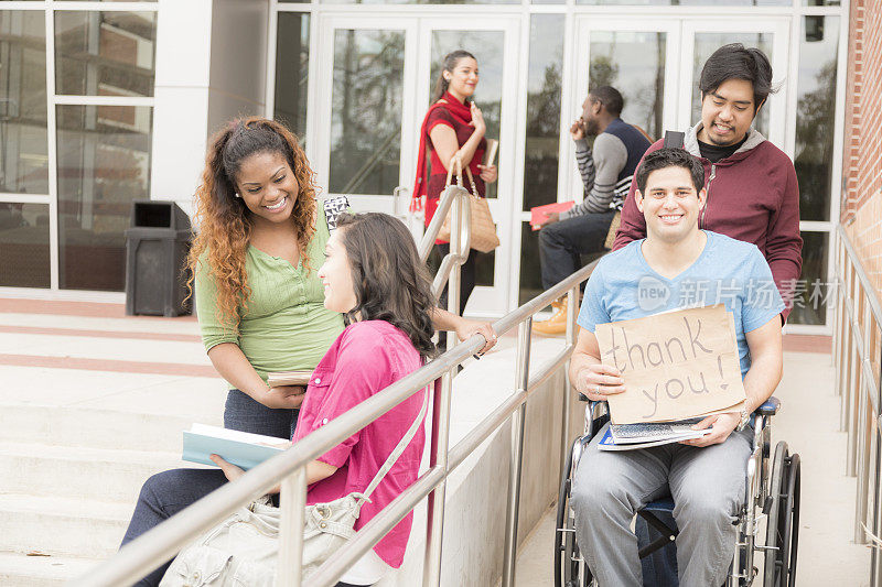 教育:帮助残疾学生下轮椅坡道。大学校园。