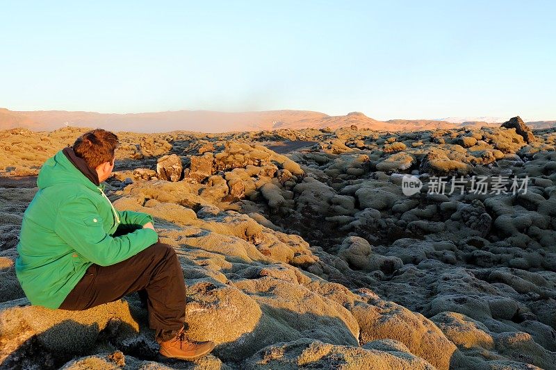 游客坐在冰岛南部的火山景观熔岩场