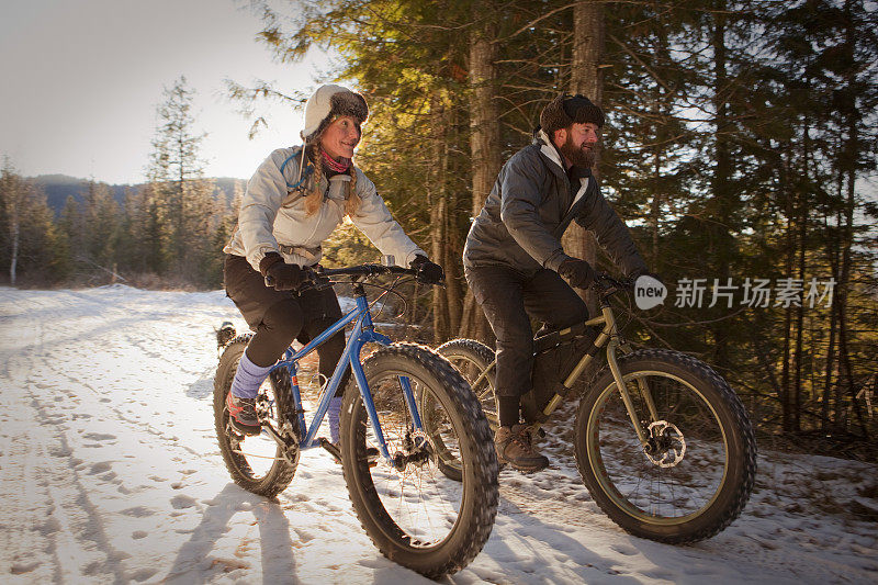 一对在雪地里骑胖自行车的夫妇