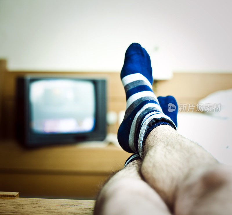 男人的腿在电视前放松
