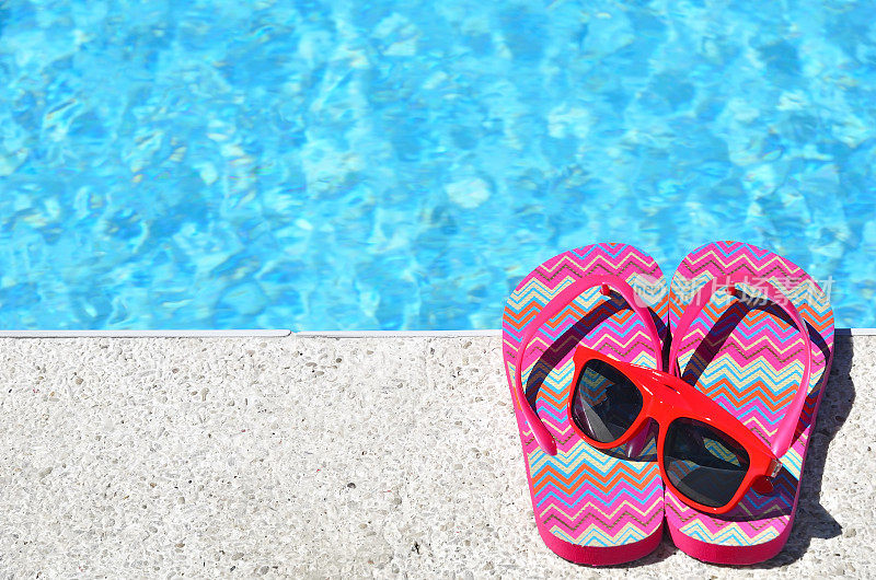 游泳池旁边的彩色拖鞋和太阳镜