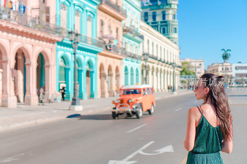 古巴哈瓦那老城区的快乐女人。小女孩旅行者背景色彩斑斓的房子