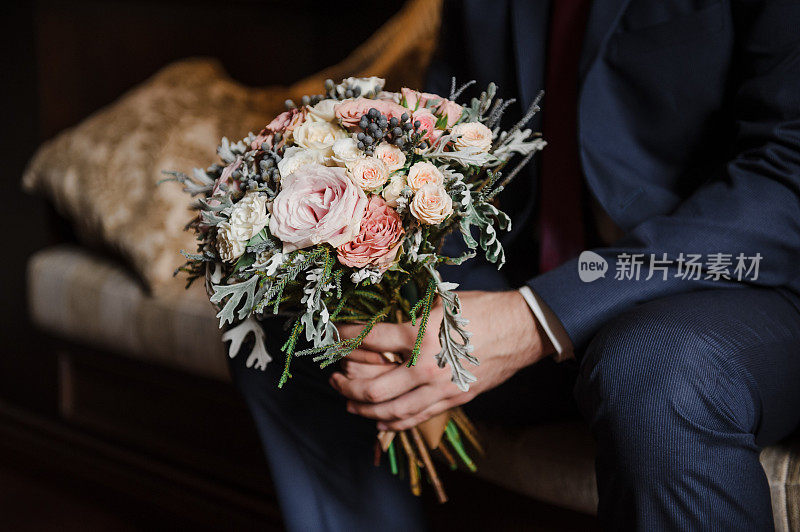 美丽的新娘花束。婚礼花艺。新郎手里拿着一束花。
