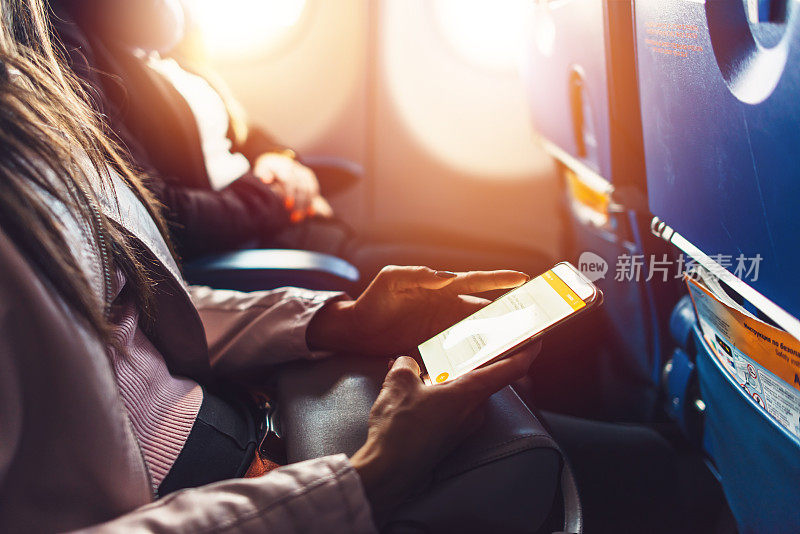 女性手握智能手机坐在飞机上的特写