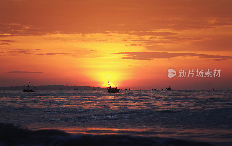 美丽明亮的海景，红色的黎明，蓝色的大海和渔船的剪影