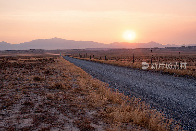 荒凉的乡村泥土和砾石路在一个朦胧的黄昏沙漠