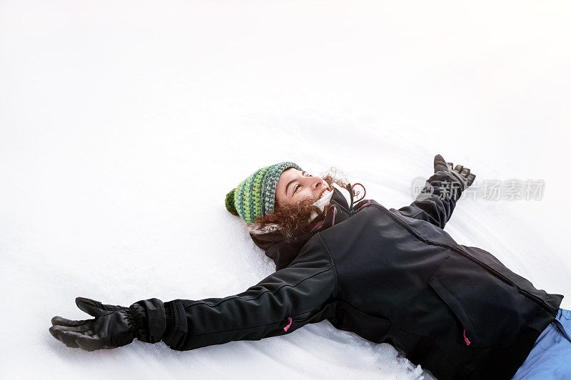 快乐快乐的女孩躺在洁白干净的雪地上