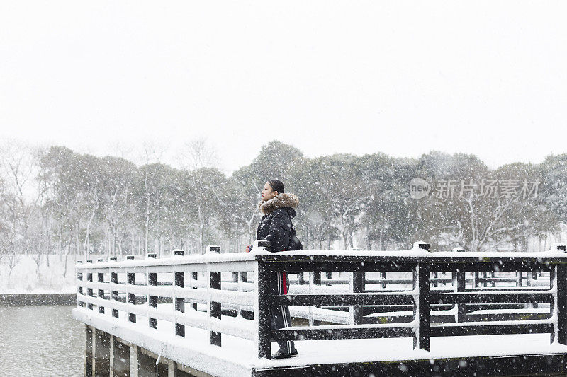 一个女人站在白雪覆盖的木桥上的宁静景象