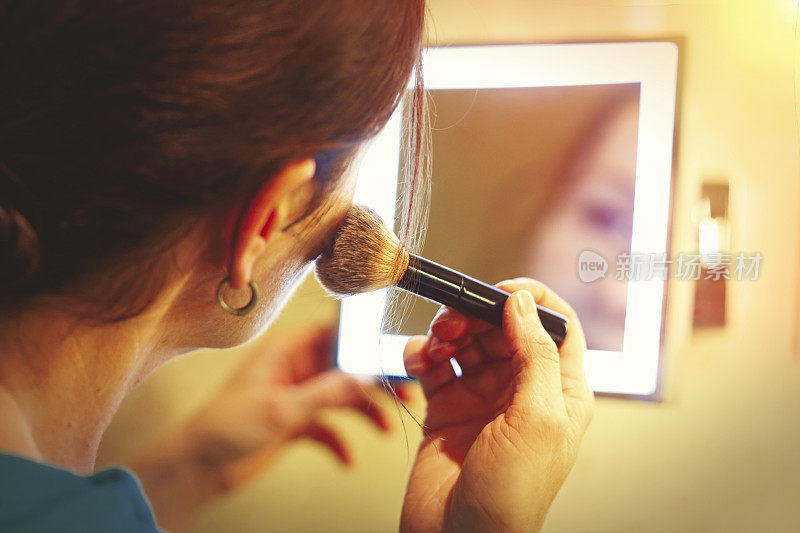 中年妇女正在用刷子化妆