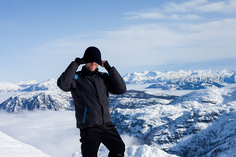 一名年轻的滑雪者，在一个阳光明媚的冬日里，享受着从奥地利滑雪场山顶上俯瞰的景色