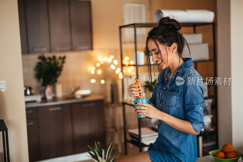 年轻女子在厨房里做橙汁