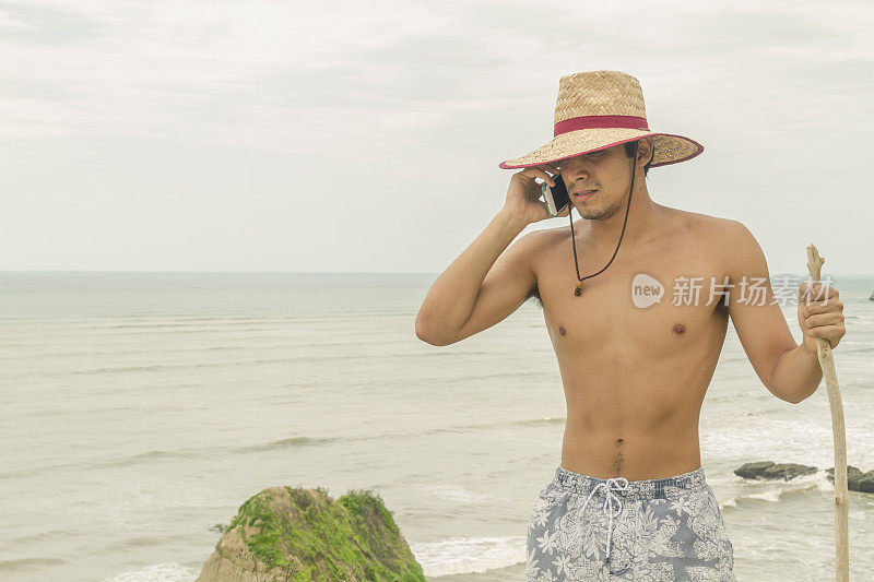 一个拉丁美洲壮汉在海滩上打电话。