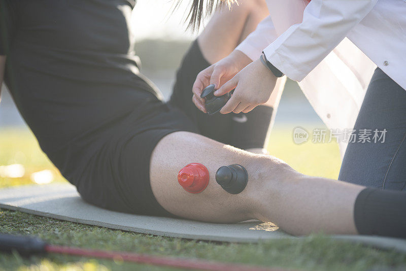 年轻的足球运动员正在接受一名年轻女医生的理疗。