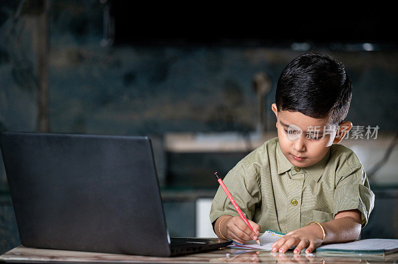 小男孩用笔记本上网上课，在家用笔记本写字。