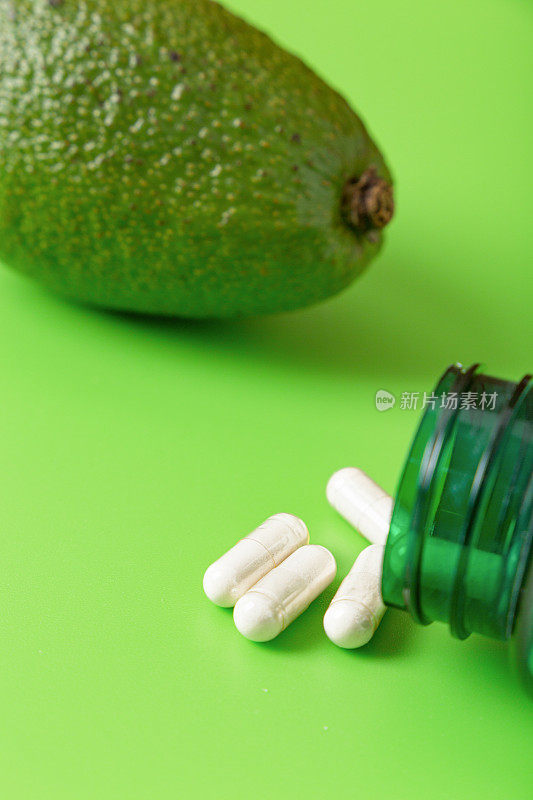绿色背景的药丸和维生素鳄梨