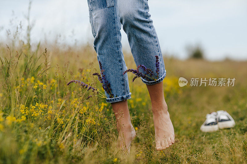 年轻女子赤脚走在绿色的春草上