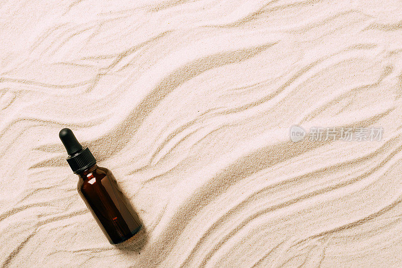 瓶精华油沙滩沙滩背景彩妆产品。抽象讲台上的产品介绍在沙的背景