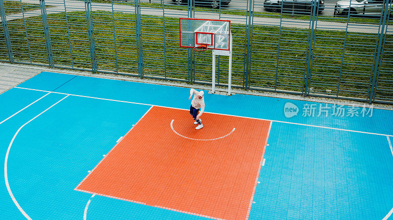 一个男人在多彩的户外操场上打篮球的鸟瞰图