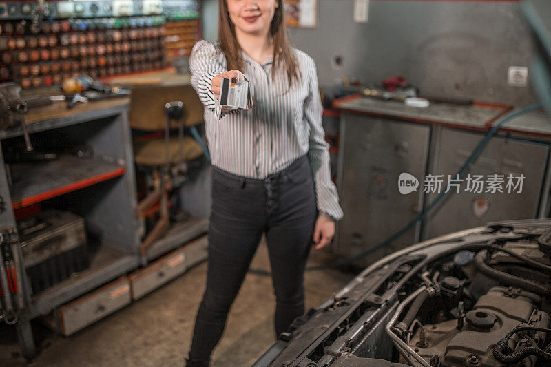 一名年轻女子在汽车修理店刷卡