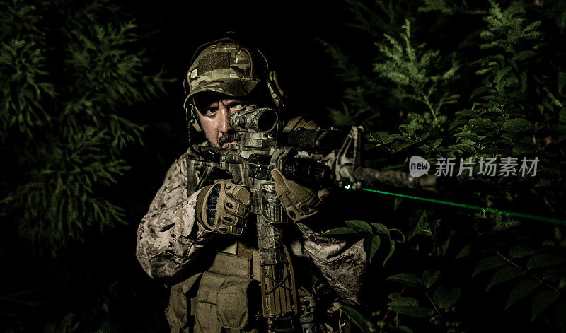 夜间军事特殊行动操作员正在用绿色激光瞄准步枪