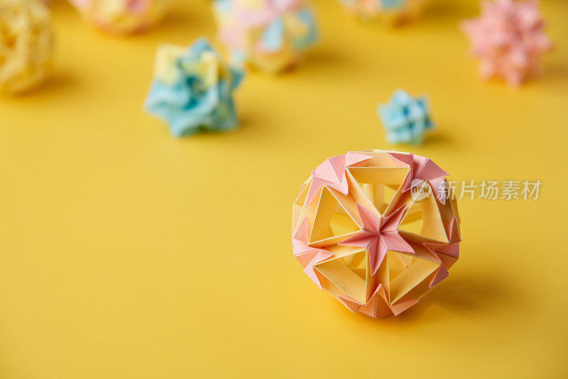 Set的multicolorÂ手工制作modularÂ折纸球或Kusudama孤立在黄色背景。视觉艺术，几何学，折纸艺术，纸工艺品。特写，选择性聚焦，复制空间。