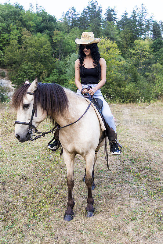 一个女牛仔骑着她的马绕着牧场转