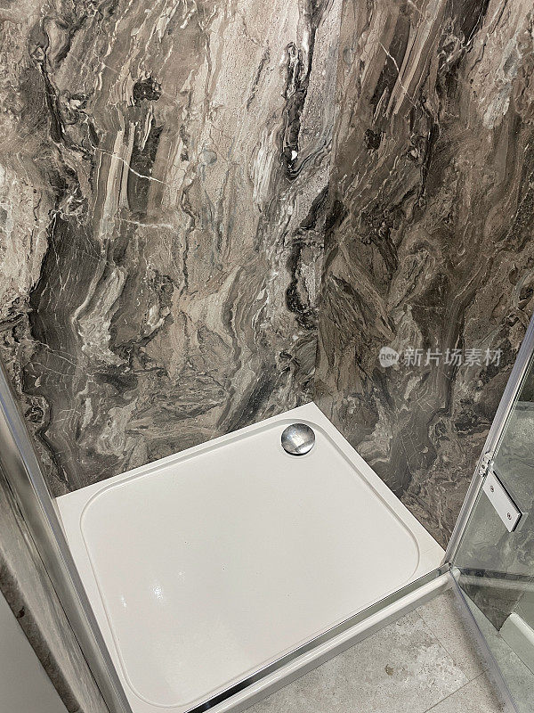现代浴室形象，玻璃门后面的大型矩形独立淋浴间，方形白色淋浴盘，镀铬排水，黑色、灰色和白色大理石墙砖，现代浴室室内设计