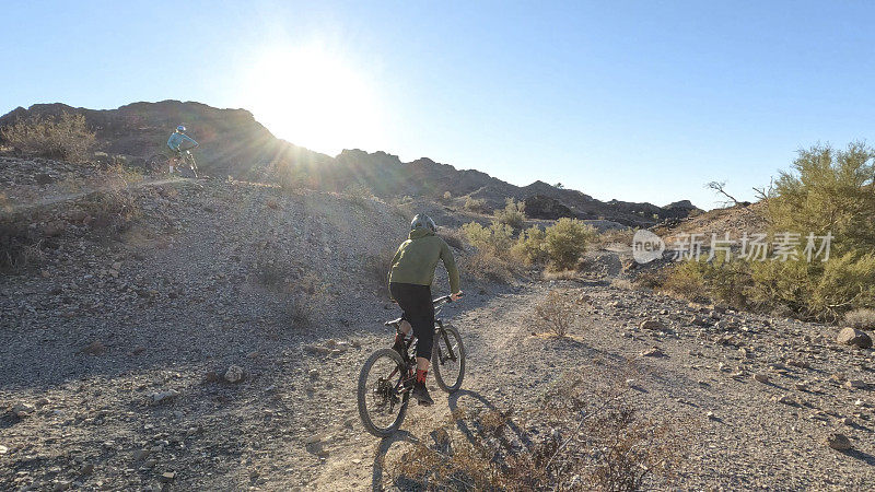 山地自行车手沿着沙漠小路行进