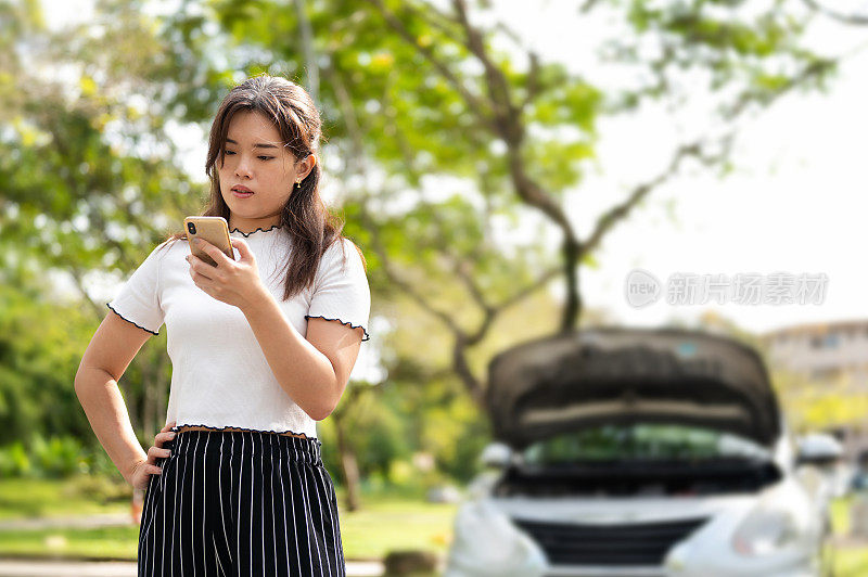 一名亚洲妇女驾车在路上抛锚，试图请求路边援助