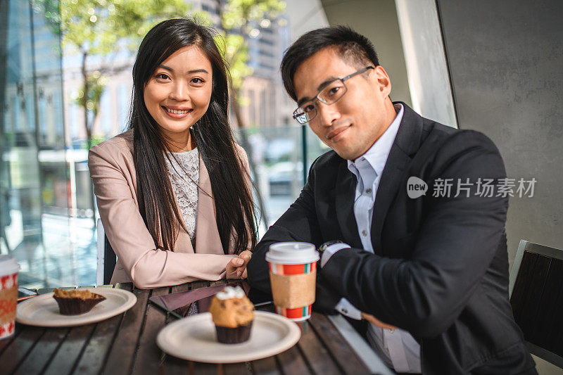 亚洲女商人和对着镜头微笑的商人