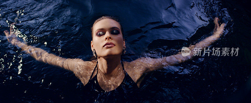 优雅的女人从水中浮现。用摄影机调情。奢华的美容护理隐喻