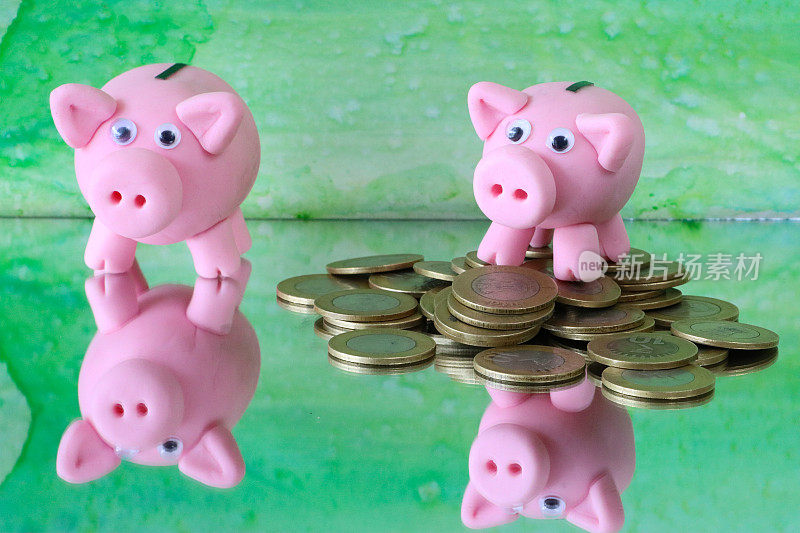 特写图像的猪储蓄罐与一堆硬币在镜子表面，重点是前景，斑驳的绿色背景，家庭财务和储蓄的概念
