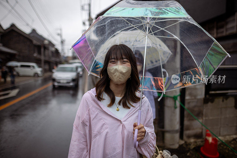 年轻女子在雨天走在传统的日本村庄