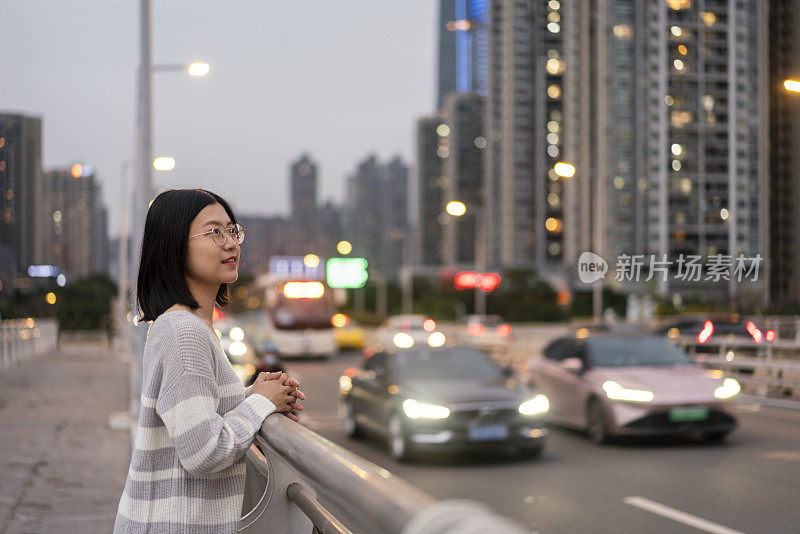 在市中心的一座桥上，一位亚洲妇女望着远方