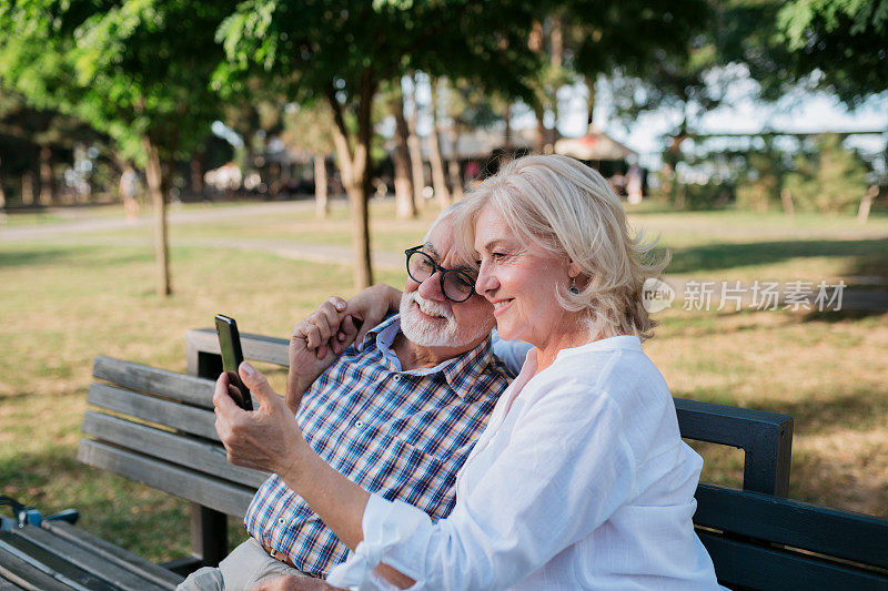 一对年迈的夫妇坐在公园长凳上