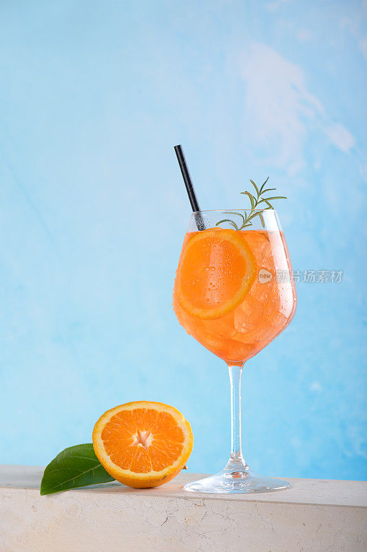 经典的意大利开胃酒鸡尾酒，在浅蓝色的背景上加入冰块和一片橙子