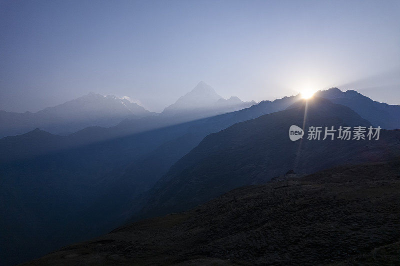 日落在山上，山峰的阴影和一个晴朗的天空