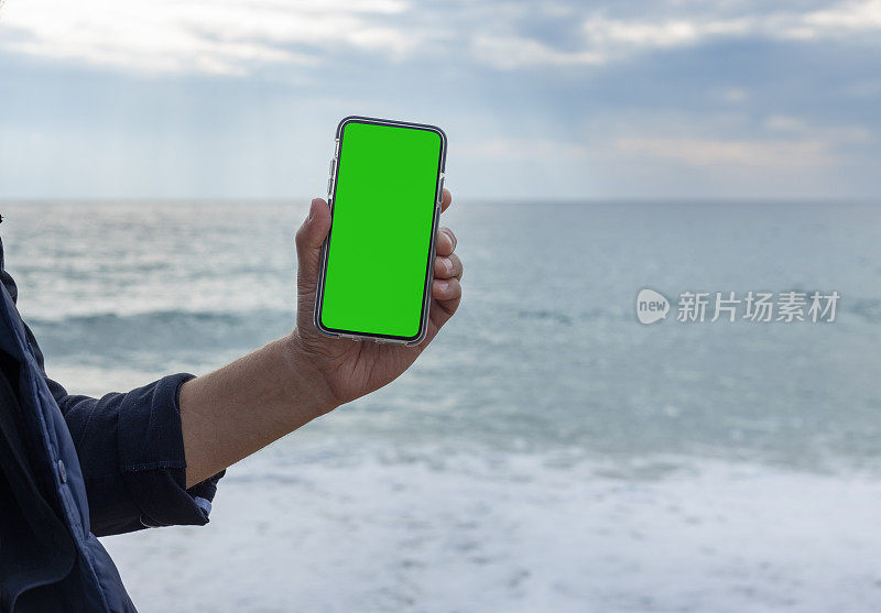 一个男人的手指着一个空白的绿色屏幕的手机