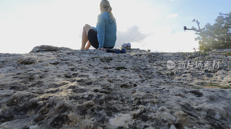 成熟的女徒步旅行者在远山的山顶上放松