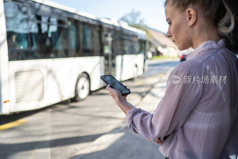 女子在等公交车时使用智能手机