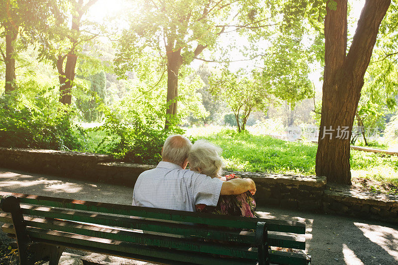 漂亮的老夫妇坐在公园的长椅上。奶奶和爷爷在户外拥抱。金婚纪念日快乐。奶奶和爷爷的浪漫照片。真正的爱。