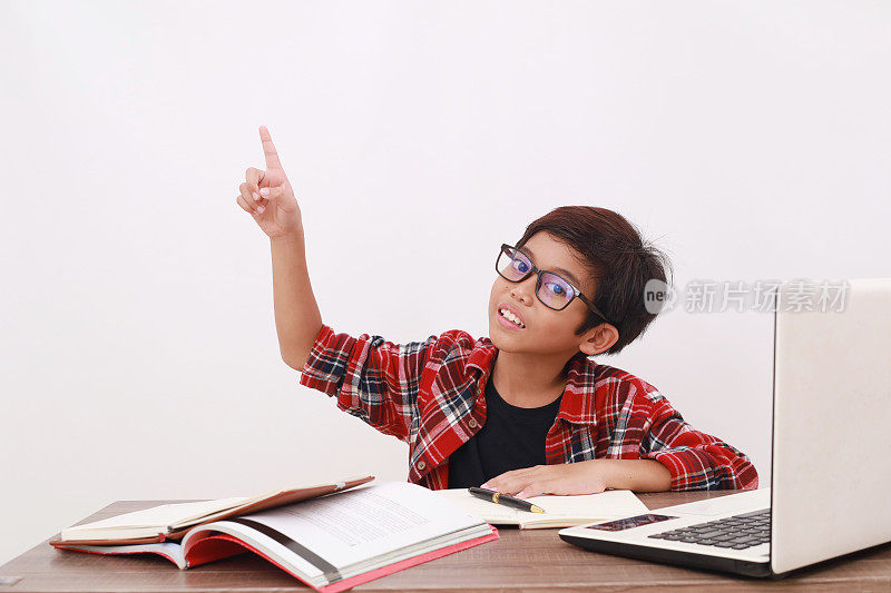 亚洲学生在用书本和笔记本电脑学习时指着上面。隔离在白色背景上
