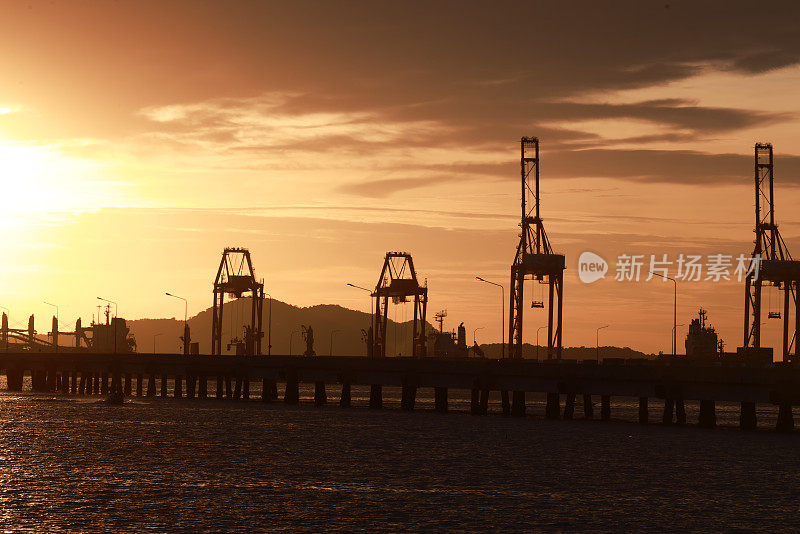 傍晚在港口、海上、河码头。工业起重机的轮廓。港口风景。明亮的夕阳，剪影动力起重机在海港，进出口的概念。