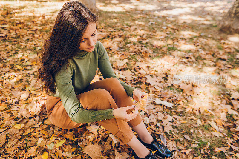 秋天的一天，一个悲伤的年轻女子坐在公园里