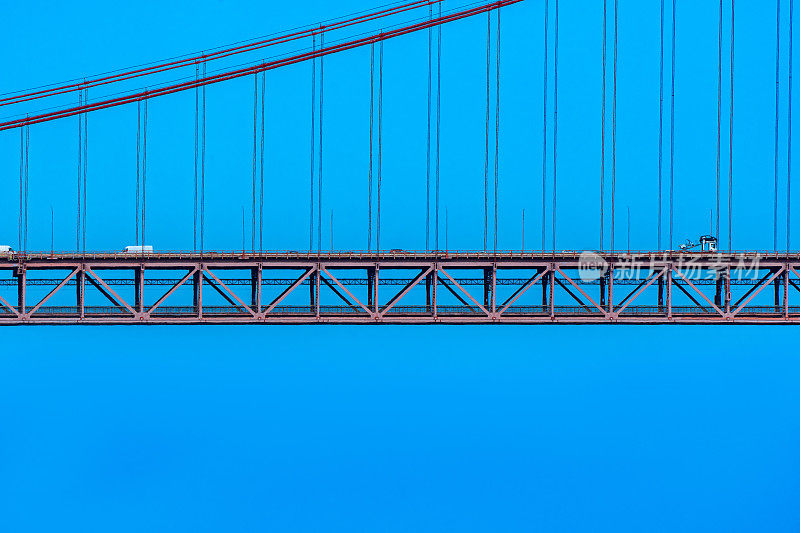 4月25日的部分悬索桥，红色钢索支撑着结构，在晴朗的蓝天下，汽车、货车和卡车在此循环进入里斯本。